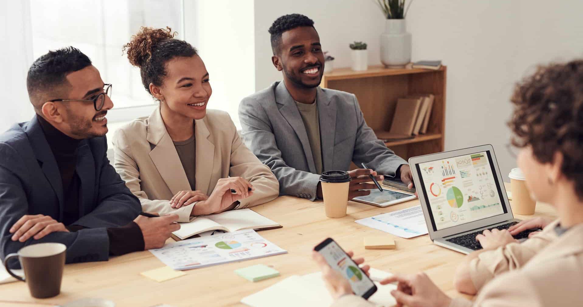 Menschen, die mit Laptop an einem Tisch sitzen.