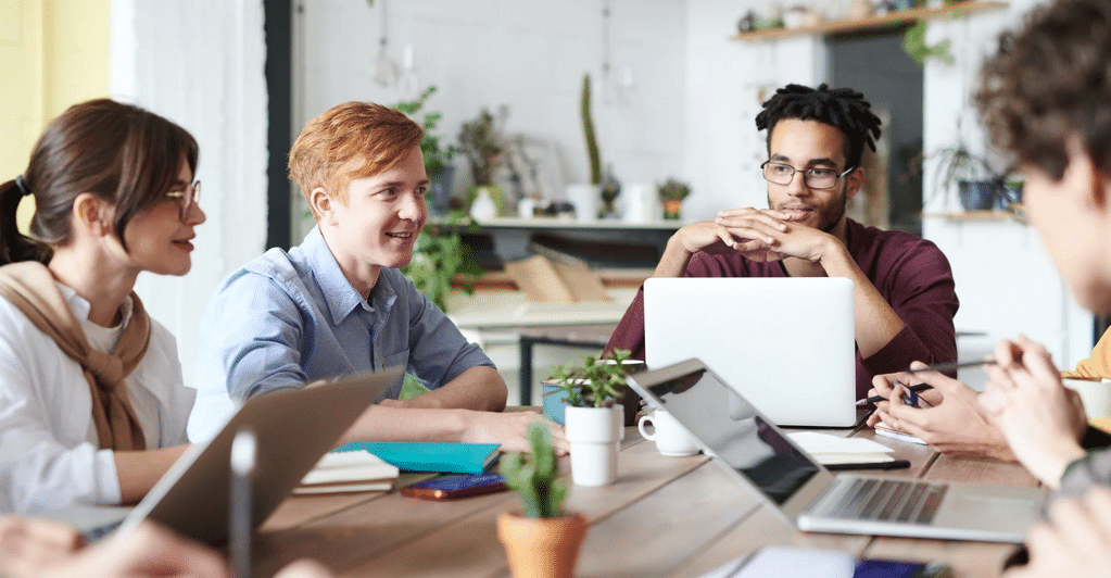 Menschen, die mit Laptop an einem Tisch sitzen