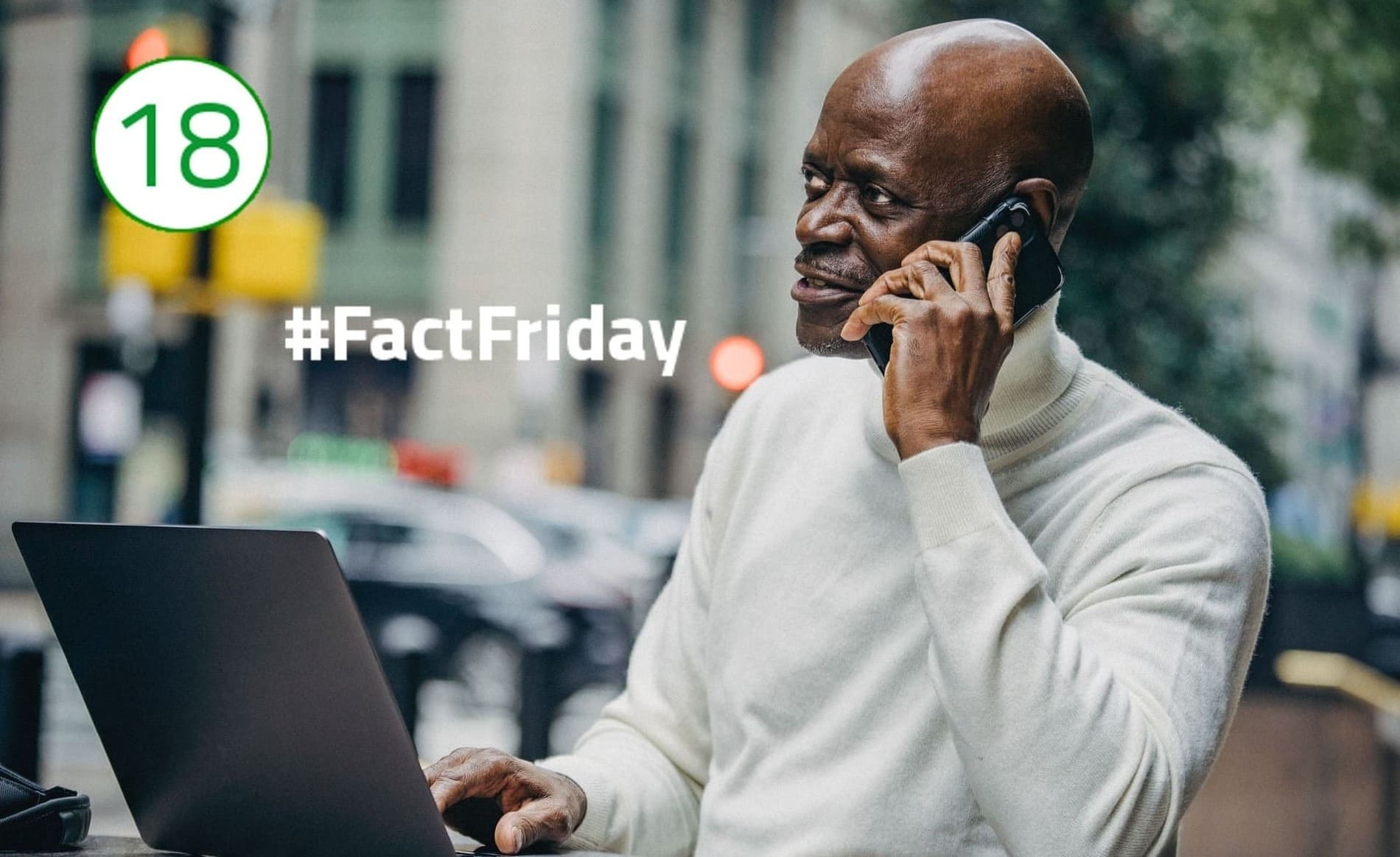 Gute Führungskraft #FactFriday Ein Mann in weißem Rollkragenpullover telefoniert, während er vor einem Laptop sitzt und seine Hand auf der Tastatur abgelegt hat. Im Hintergrund ist Straßenverkehr zu sehen.