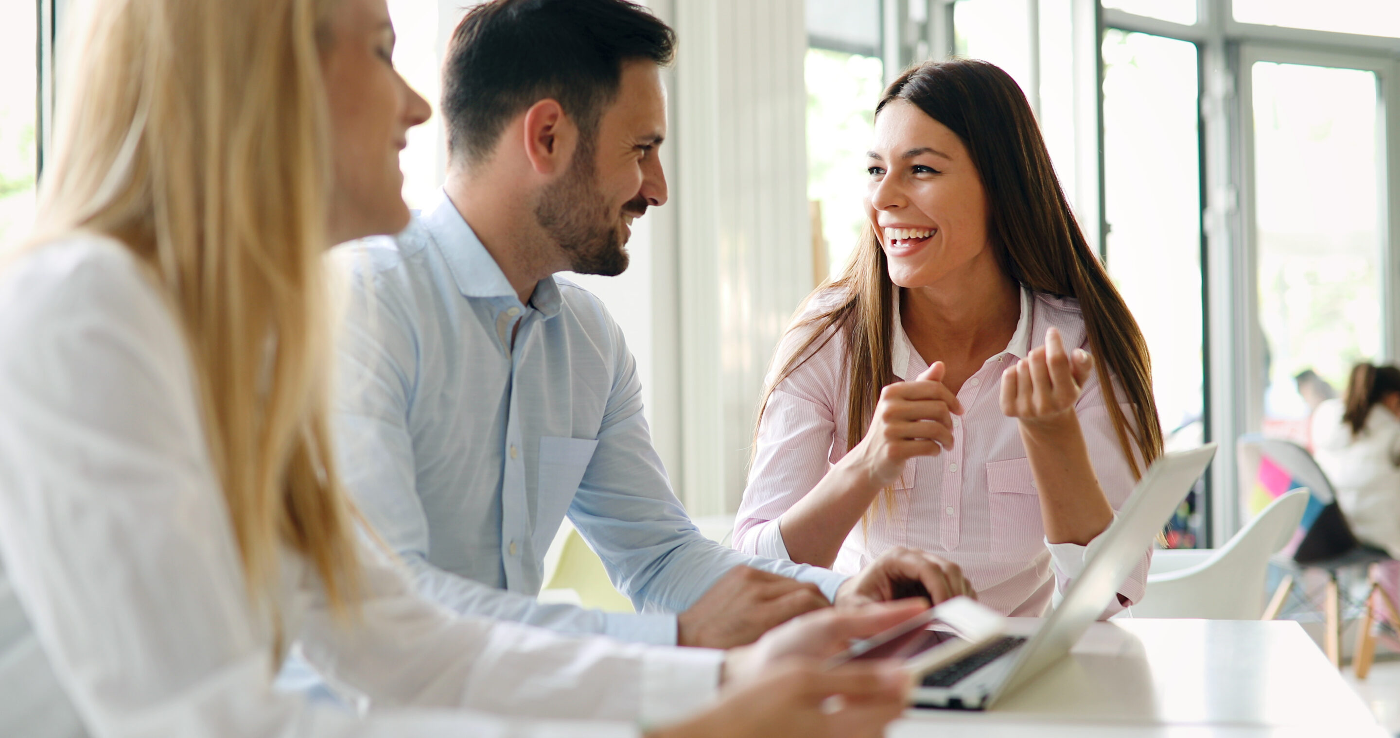 Gefährdungsbeurteilung psychischer Belastung Drei Personen sitzen an einem Tisch und unterhalten sich fröhlich.