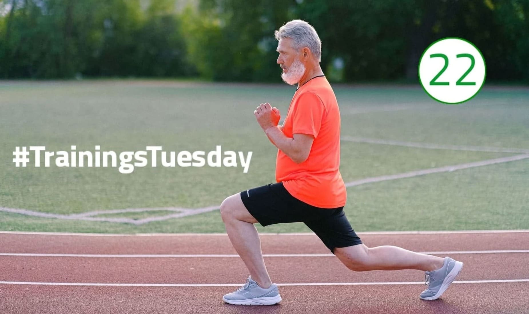 Lunges Trainings Tuesday Ein grauhaariger Mann mit weißem Bart macht einen weiten Ausfallschritt auf der Aschebahn. Er ist von der Seite zu sehen: Seine Arme hält er nah vor seinem Oberkörper; sein Blick geht konzentriert nach vorne. Er trägt ein knallorangenes T-Shirt und eine schwarze kurze Hose.