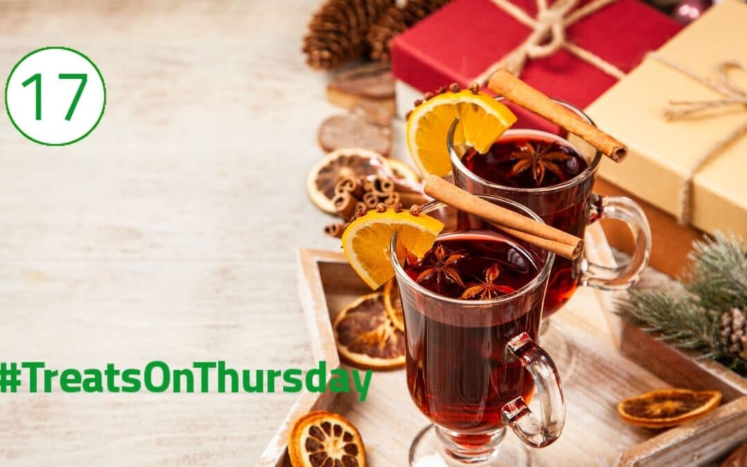 In der rechten Hälfte stehen zwei Gläser gefüllt mit Glühwein. Auf ihnen liegen jeweils eine Zimtstange und eine Orangenscheibe, in der Nelken stecken. Im Glas schwimmt ein Anisstern. Im Hintergrund liegen verpackte Geschenke.