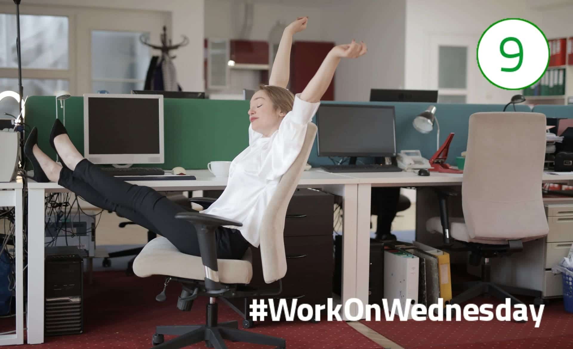#WorkOnWednesday – Pausen aktiv nutzen! Frau mit weißer Bluse sitzt auf einem Bürostuhl am Schreibtisch, Füße auf dem Tisch und die Arme in die Höhe gestreckt.